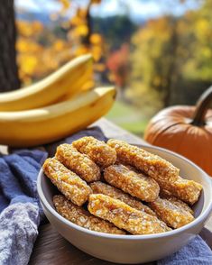 a bowl full of food sitting on top of a table next to bananas and pumpkins