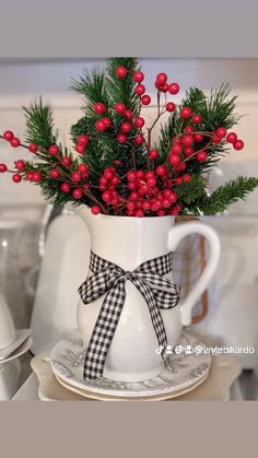 a white coffee cup filled with red berries and greenery on top of a plate