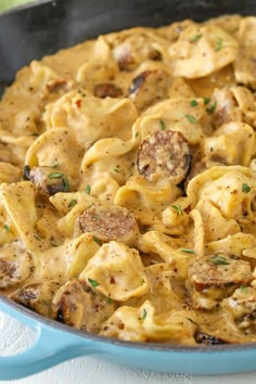 a blue skillet filled with pasta and meat