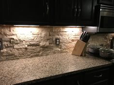 a kitchen with granite counter tops and black cabinets, along with wooden utensils