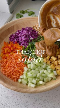 a bowl filled with different types of vegetables on top of a white counter next to a wooden spoon