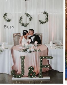 a couple sitting at a table in front of christmas decorations and lights on the wall