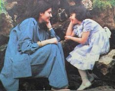 two women sitting on rocks talking to each other