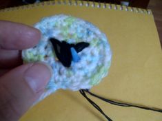 a small crocheted brooch with a black bird on it