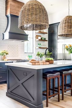 a large kitchen island with stools in front of it and two hanging lights above the island