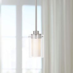 a light fixture hanging from a ceiling in a room with white curtains and drapes