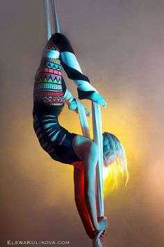 a woman is doing aerial acrobatics on a pole