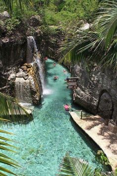 people are swimming in the water near a waterfall