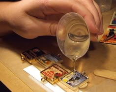 a person pouring wine into a glass on top of a wooden table next to other items