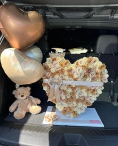 there is a heart shaped box with roses and balloons in the back of a car