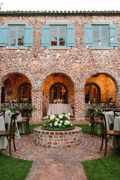 a brick building with tables and chairs set up for a wedding reception in front of it