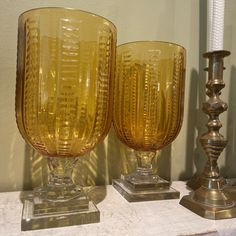 two yellow glass goblets sitting next to each other on top of a table