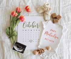 a baby announcement with tulips and other items laid out on a white sheet