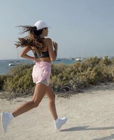 a woman running on the beach with her hair blowing in the wind