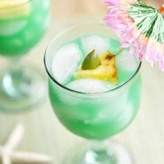 a close up of a drink in a glass with an umbrella on the top and two other glasses next to it