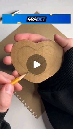 someone is holding a paper heart with a pencil in it