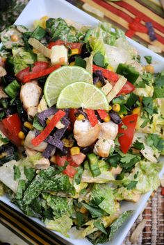 a salad with chicken, lettuce, corn, and tomatoes on a plate