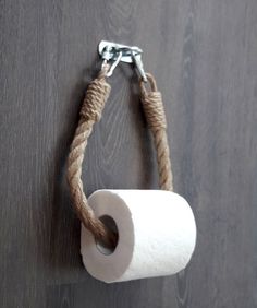 a roll of toilet paper hanging from a rope on a wooden wall with a metal hook