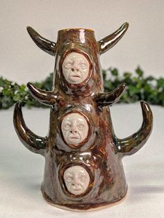 three faces on the top of a vase