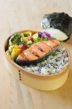 a wooden bowl filled with rice and salmon next to a piece of broccoli