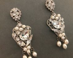 "Beautiful & unique vintage chic earrings set that features freshwater pearls and various shapes of crystals placed on antique silver plating. These lovely earrings will add an elegant finishing touch to your wedding look and also are a great accessory for any formal affair. READY TO SHIP DETAILS * Measures 1\" wide by 2.5\" long * Lightweight & comfortable BRIDAL JEWELRY: https://www.etsy.com/shop/AGoddessDivine?ref=si_shop§ion_id=14361473 COMBS, CLIPS AND PINS: https://www.etsy.com/sho Ornate Clip-on Earrings For Evening Wear, Vintage Clip-on Crystal Earrings For Wedding, Vintage Pearl Drop Clip-on Earrings For Party, Vintage Clip-on Chandelier Earrings For Formal Occasions, Luxury Vintage Clip-on Pearl Earrings, Statement Earrings Wedding, Vintage Chic Wedding, Bridal Statement Earrings, Crystal Bridal Earrings