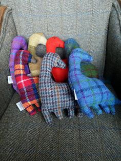 several stuffed animals are sitting on the back of a gray chair with plaid covers and wool mittens