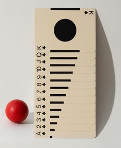 a red ball sitting on top of a white table next to a ruler with numbers