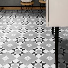 a black and white tiled floor with two chairs next to it in front of a counter