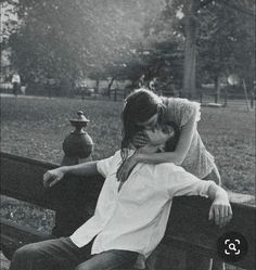 black and white photograph of two people kissing on a park bench