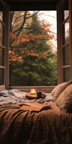 a bed sitting in front of a window with an open book on top of it