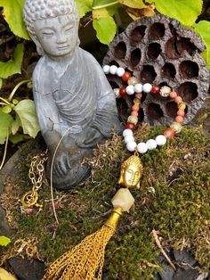 "\"There is no path to happiness: happiness is the path.\" -Gautama Buddha This statement piece features a pendant comprised of a gold tone metal Buddha head bead, a rough cut Yellow Opal bead and a gold tone cable chain tassel with gold tone tassel cap. The full pendant is 6'' in length and hangs from a 29'' gemstone bead and gold tone cable chain necklace with gold tone toggle clasp. Beads include Howlite, Fire Agate, Banded Agate, matte Goldstone, matte Tiger's Eye & metal plated strung o Gautama Buddha, Yellow Opal, Cable Chain Necklace, Buddha Head, Fire Agate, Banded Agate, Tiger's Eye, Toggle Clasp, Rough Cut