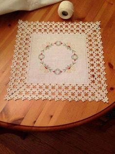 a white doily sitting on top of a wooden table next to a ball of yarn