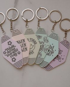 six keychains with different designs on them sitting next to each other in front of a marble surface