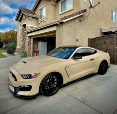 a white mustang parked in front of a house