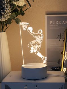 a lamp with a basketball player on it sitting on top of a table next to a vase