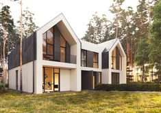 a white house with black shutters on the front and windows in the back is surrounded by trees