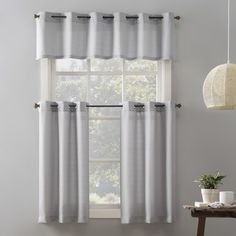 a window with white curtains and a potted plant next to it on a table