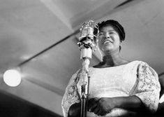 a black and white photo of a woman singing into a microphone in front of a mic