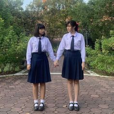 two girls in school uniforms are holding hands