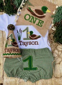 the first birthday outfit is made with green and white gingham plaid shorts, one duck