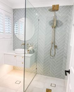 a bathroom with a walk in shower next to a white sink and mirror on the wall