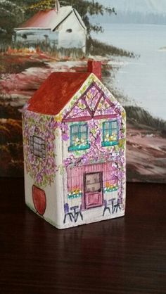 a small doll house sitting on top of a wooden table next to a wall painting