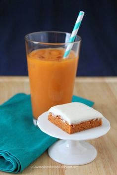 a piece of cake sitting on top of a white plate next to a glass of orange juice