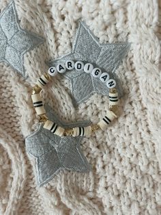 two bracelets with name charms on them sitting on a knitted blanket, next to each other