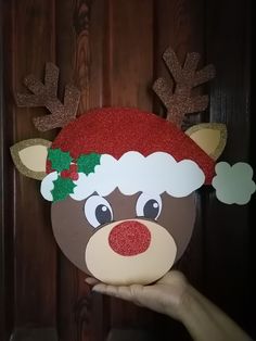 a hand holding up a reindeer mask with glitter on it's ears and nose