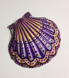 a purple and yellow scallop shell on a white wall