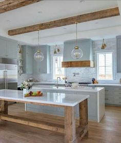 a large kitchen with an island in the middle and two pendant lights hanging from the ceiling