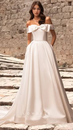 a woman in a white wedding dress standing on some steps with her hands on her hips