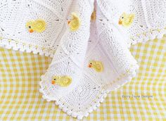 a crocheted blanket with yellow rubber ducks on it and a gingham checkered tablecloth