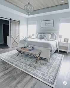 a large bed sitting on top of a wooden floor next to a white dresser and chair